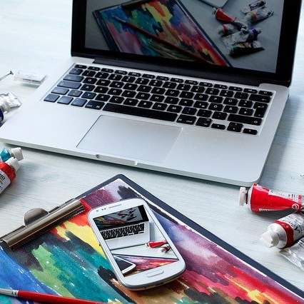 Laptop und Farben auf Tisch