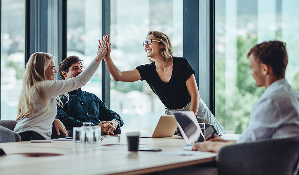Team gibt sich in einem Besprechungsraum ein High-Five