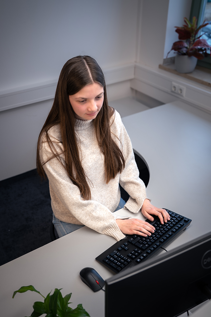 Auszubildende arbeitet konzentriert an einer Tastatur am Schreibtisch